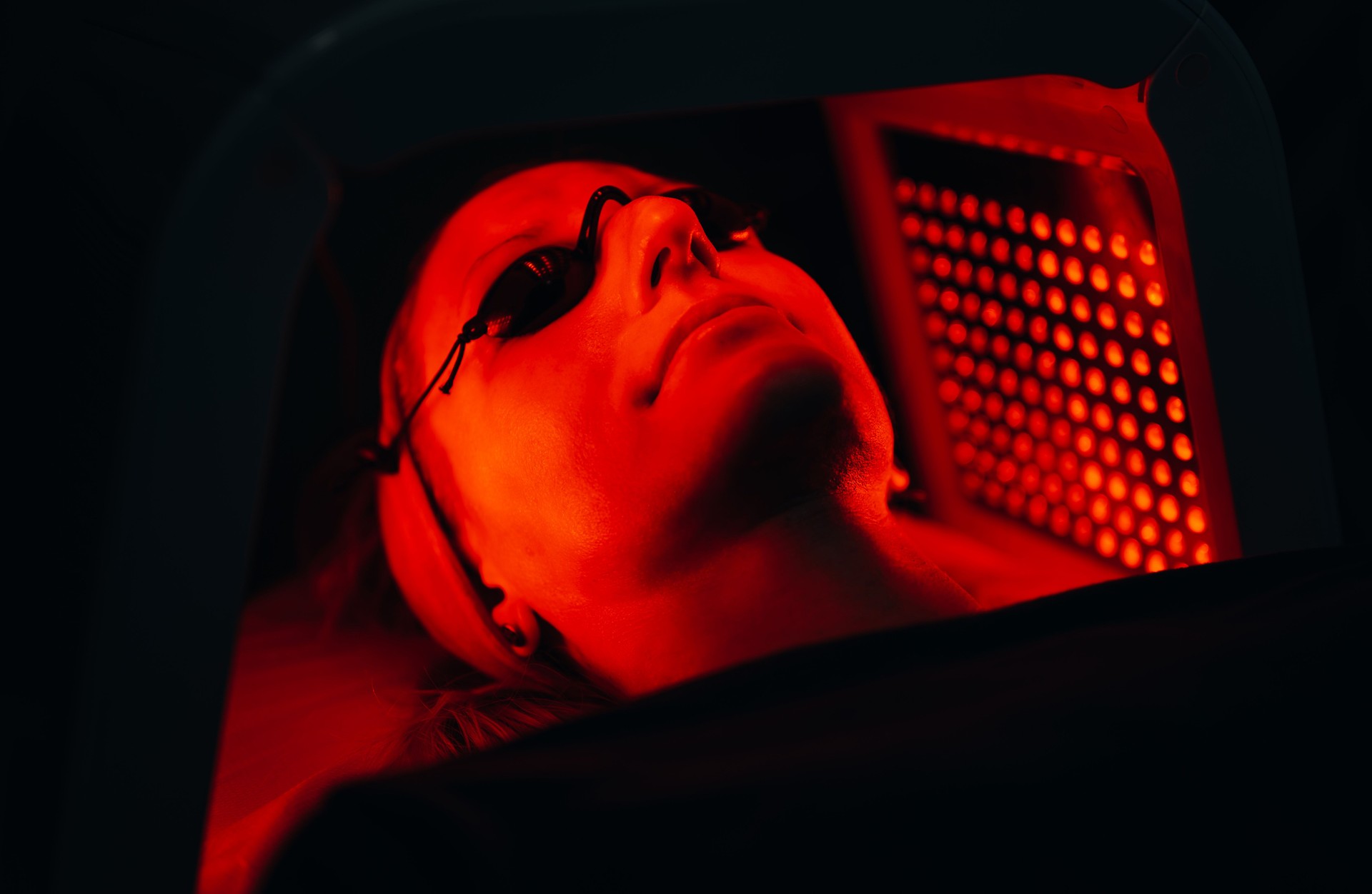 Young woman having red LED light facial therapy treatment in a beauty salon