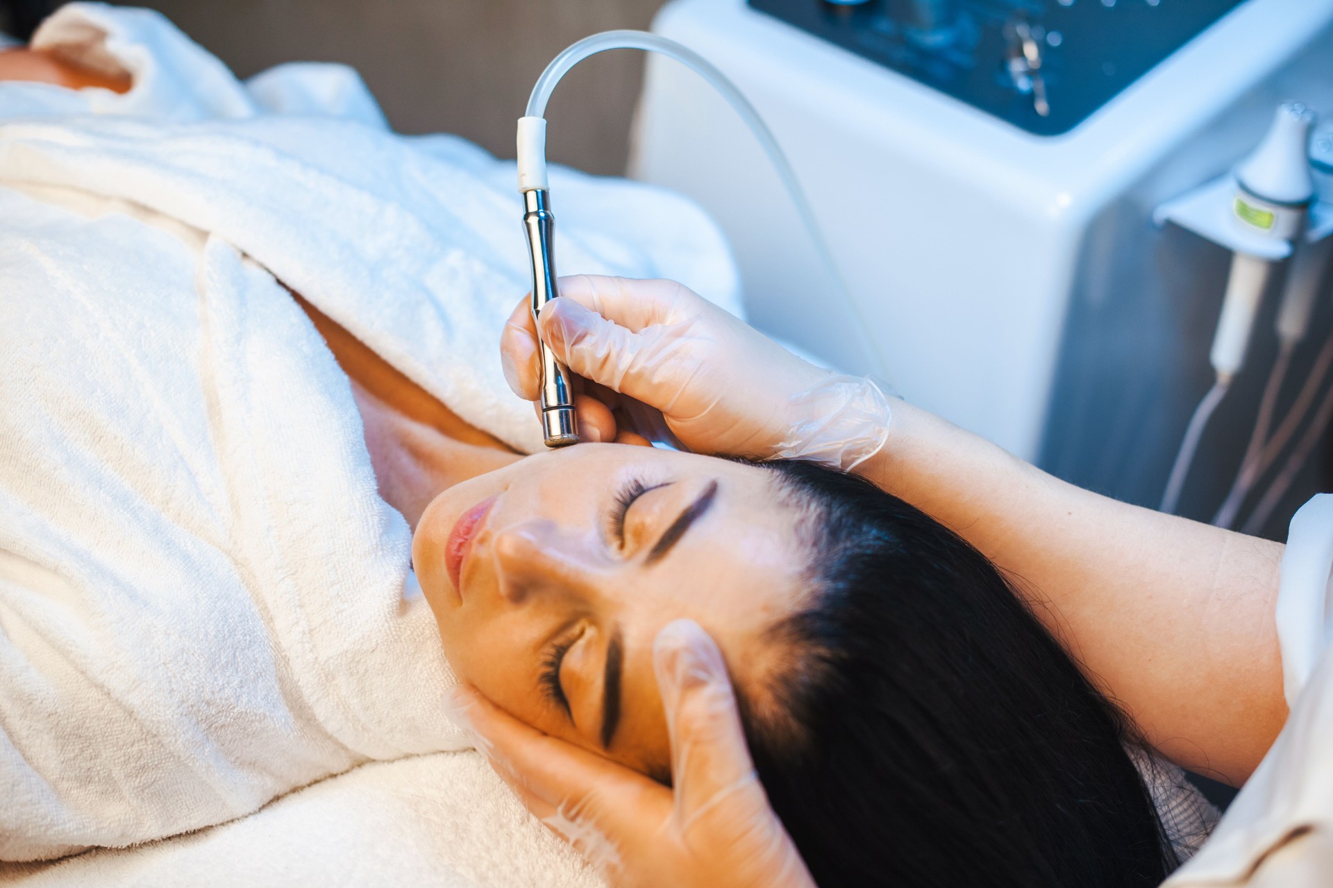 Close-up portrait of cosmetologist's hands making microdermabrasion procedure on the face of a woman in a beauty salon. Facial skin treatment. Cosmetology beauty procedure.