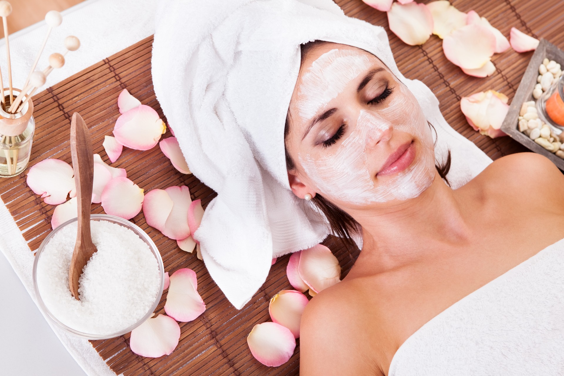 Beautiful young woman getting facial mask